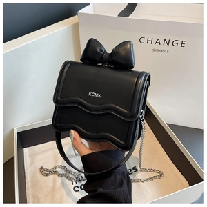 Close-up of black leather mini bag with large bow detail and silver chain strap