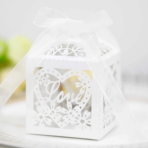Macro detail of white laser-cut wedding favor box with Love heart and organza ribbon
