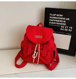 Detail of red canvas backpack featuring white drawstring closure and branded logo patch