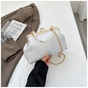 Detail of white floral jacquard shell bag with vintage gold metal frame and chain strap