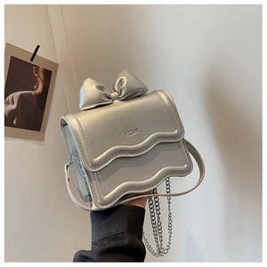 Detail of silver metallic mini bag with bow accent and stylish wavy flap design