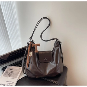Detail of vintage dark brown hobo bag with sleek leather texture and unique T-shaped pendant