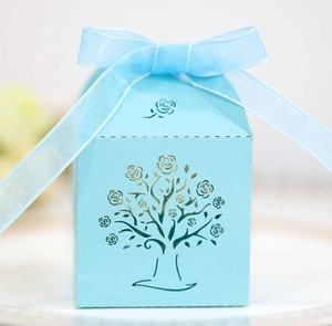 Close-up of light blue laser-cut candy box with floral tree pattern and organza ribbon