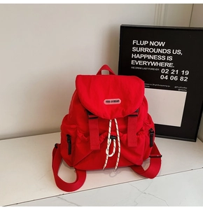 Detail of red nylon backpack showing drawstring closure and black plastic buckle system