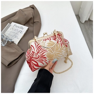 Detail of red floral embroidery on cream shell bag with golden metal handle and chain