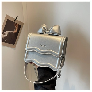 Detailed view of silver bow-knot mini crossbody bag with metal chain strap and logo