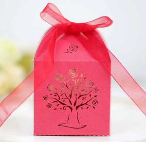 Detail of laser-cut rose tree pattern on red wedding candy box with sheer ribbon bow
