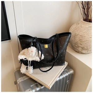 Detail of black tote bag with cat print, lychee texture and plush rabbit charm