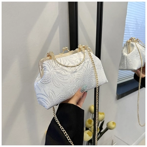 Detail of elegant beige jacquard evening bag with floral embossing and gold chain
