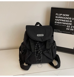 Detail of minimalist black nylon backpack featuring drawstring closure and metal brand logo