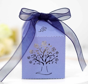 Detail of purple laser-cut candy box featuring rose tree patterns and blue organza ribbon
