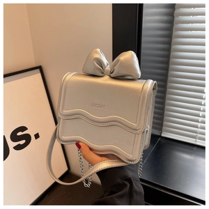 Detail of silver mini crossbody bag with metal bow and KGMK logo on wavy flap