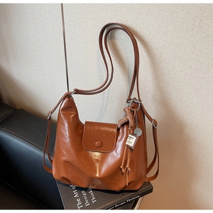 Detail shot of caramel brown vintage hobo bag with silver buckle and tassel charm