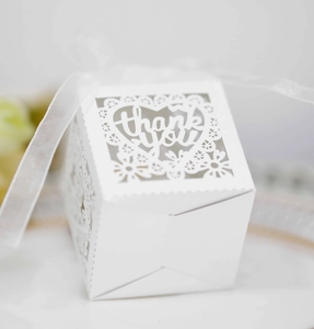 Close-up of white laser-cut lace candy box with heart-shaped Thank You motif and ribbon