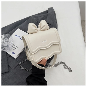 Close-up of cream white leather bag featuring bow decoration and wavy edges with chain strap