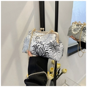 Elegant handheld view of shell-shaped jacquard handbag with pearl handle and metal chain