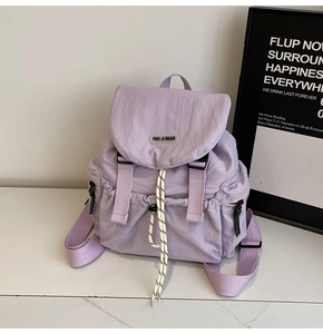 Detail of light purple nylon backpack with flap closure, buckles, and drawstrings