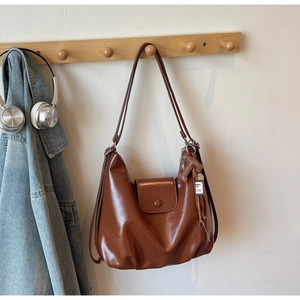 Detail of a shiny dark brown vintage hobo bag hanging with stylish tassel accessory