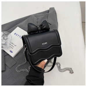 Close-up of black bow shoulder bag with scalloped edge flap and silver chain strap detail