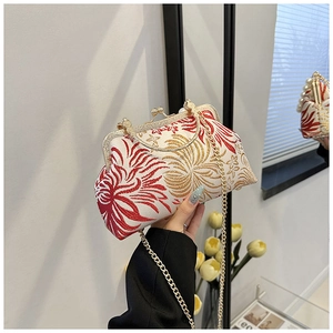 Macro detail of floral embroidery and vintage gold metal clasp on a shell-shaped bag
