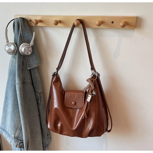 Detail of caramel brown leather tote bag with a small horse charm and vintage texture