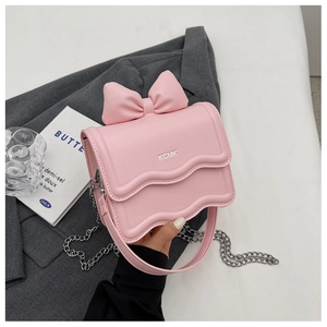 Close-up of pink mini crossbody bag with bow decoration and gold chain strap details