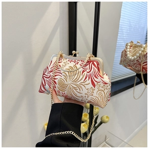 Detail of vintage style embroidery shell bag with red floral pattern and golden kiss lock