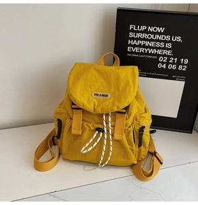 Detail of yellow nylon backpack with drawstring closure, top flap and buckle decoration