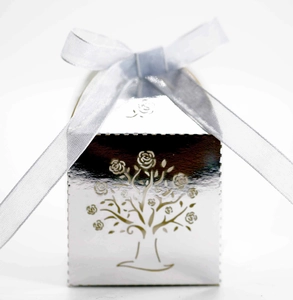 Detail of silver laser-cut candy box with hollow tree design and grey satin ribbon bow