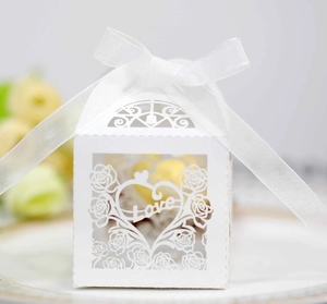 Macro view of white laser-cut hollow candy box with rose patterns and Love design