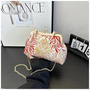 Detailed macro view of the classical floral embroidery and golden metal clasp on shell bag