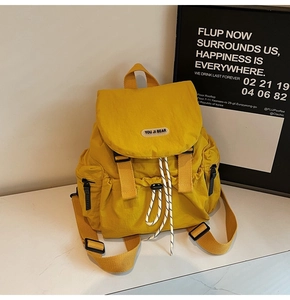 Detail of yellow nylon backpack featuring drawstring closure and secure buckle straps