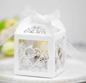 Close-up of laser-cut white favor box with Love heart pattern and satin ribbon