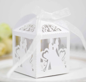Macro detail of laser-cut wedding favor box with bride and groom silhouette and ribbon