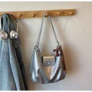 Detail of silver metallic tote bag featuring a leather tassel and letter T pendant charm