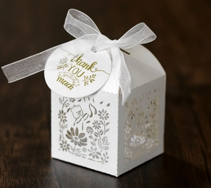 Detail of white laser-cut gift box with floral bear patterns and a white organza bow