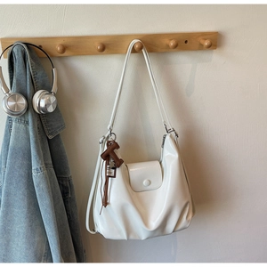 Detail of white PU leather hobo bag with round buckle and brown T-shaped charm pendant