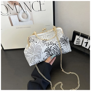 Close-up of vintage shell bag with black floral pattern and golden metal frame