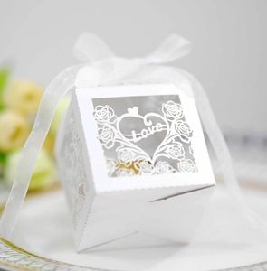 Macro detail of white laser-cut wedding candy box with Love text and ribbon on a plate