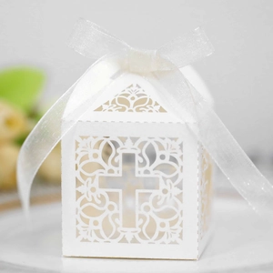 Macro detail of laser-cut white favor box with elegant cross pattern and white ribbon