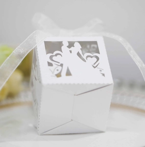 Macro detail of laser-cut wedding favor box with bride groom heart silhouette and white bow