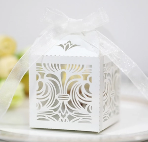 Détail de boîte de mariage blanche découpée au laser avec motifs baroques et ruban organza