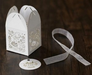 Detail of laser-cut white gift box featuring floral puppy hollow patterns and silk ribbon