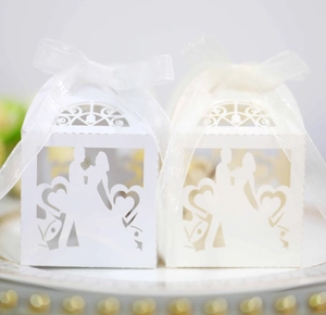 Detail of laser-cut wedding favor boxes with groom and bride silhouette and organza ribbon