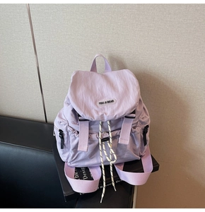 Close-up of lavender nylon backpack with white cord drawstring and woven fabric strap
