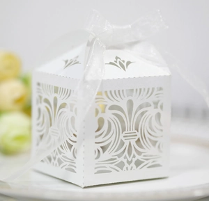 Détail d'une boîte à bonbons de mariage découpée au laser avec un ruban de soie blanc