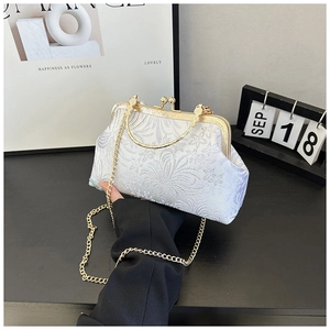 Detailed shot of silver brocade seashell bag with pearl clasp and golden chain strap