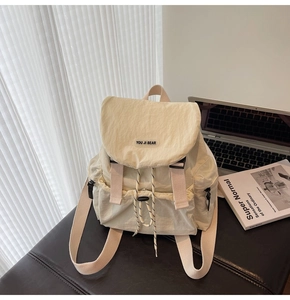 Detail of minimalist beige backpack featuring a brand label and buckle on high-quality nylon
