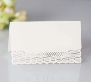 Macro detail of laser-cut white lace paper table card with intricate floral patterns