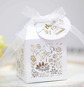 Close-up of white cutout candy box with ribbon and thank you tag for weddings